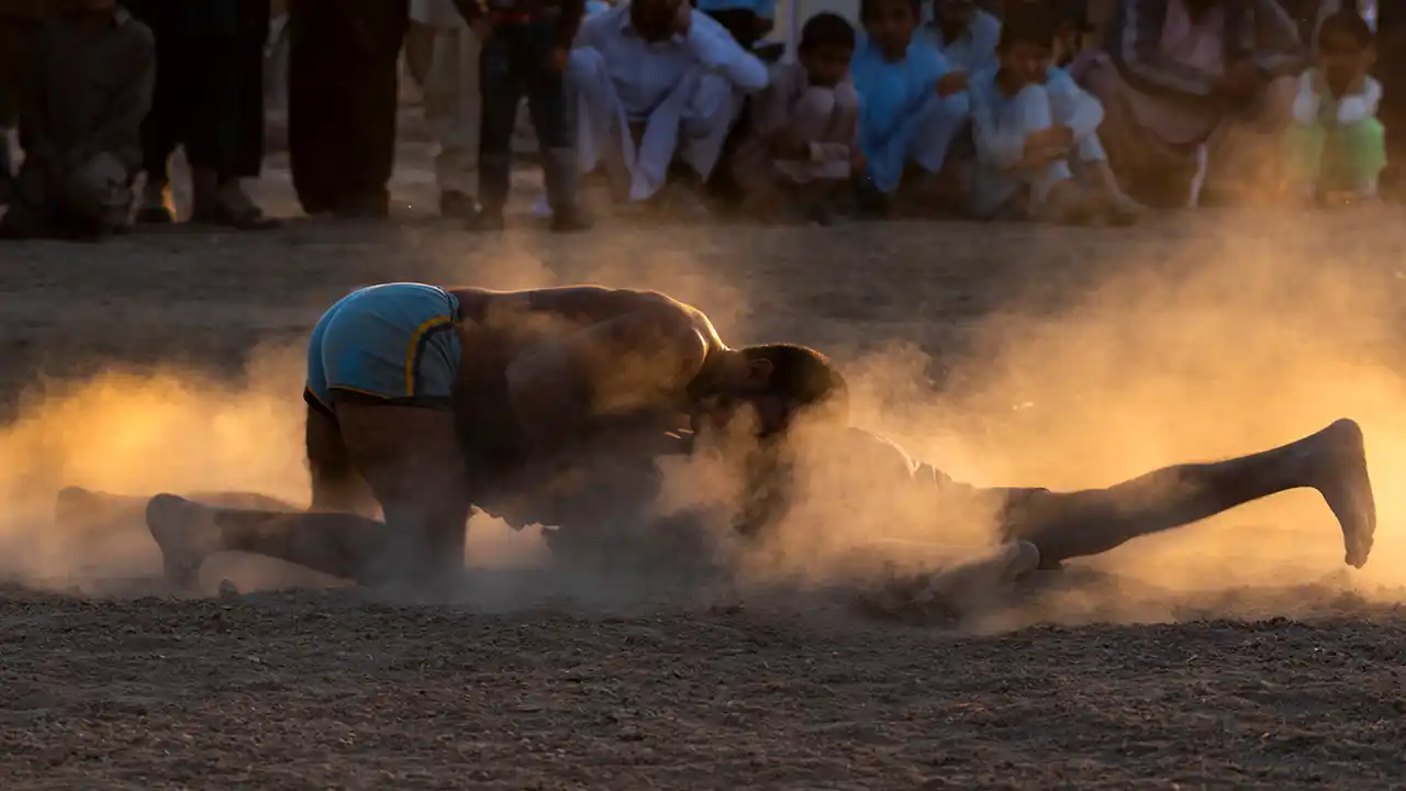 Kabaddi competitors wrestle in the dust